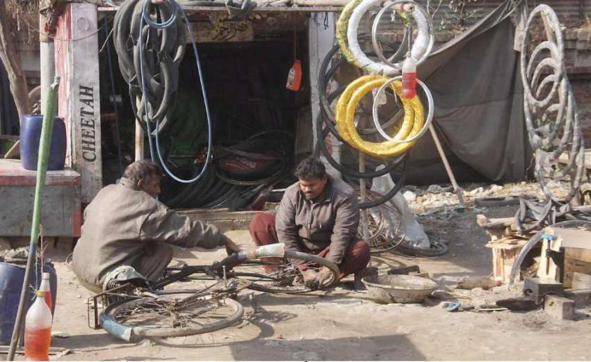 لاہور: ایک کاریگر سائیکل کو پنکچر لگا رہا ہے۔