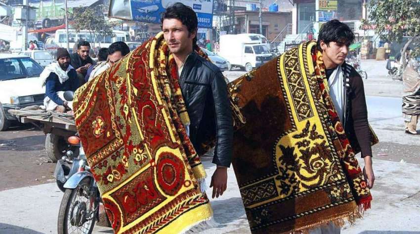 اسلام آبا د: دو محنت کش قالین فروخت کے لیے پھیری لگا رہے ہیں۔