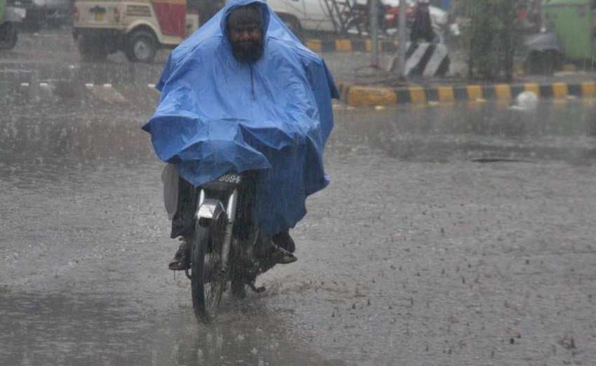 لاہور: شہر میں ہونے والی بارش کے دوران موٹر سائیکل سوار پلاسٹک ..