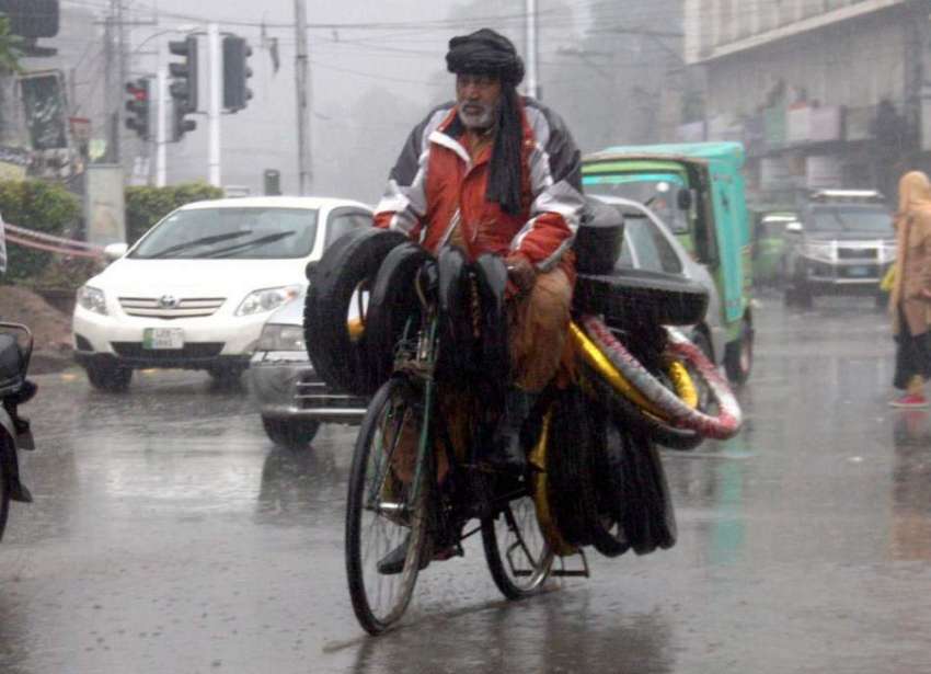 لاہور: شہر میں ہونے والی بارش کے دوران ایک محنت کش سائیکل ..