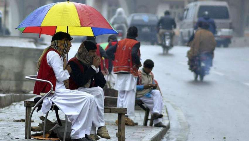 راولپنڈی: ڈھولچی بارش سے بچنے کے لیے چھتری تانے سڑک کنارے ..