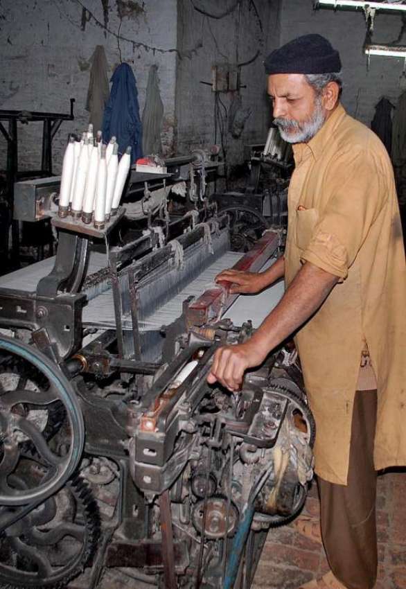 فیصل آباد: ایک مزدور پاور لوم پر کام میں مصروف ہے۔