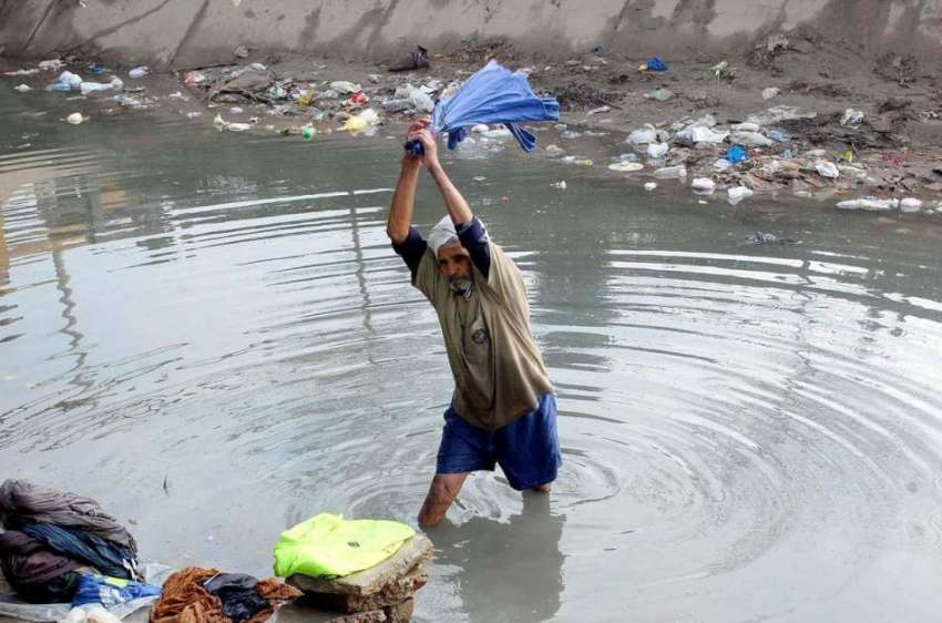 فیصل آباد: ایک دھوبی نہر میں کپڑے دھو رہا ہے۔