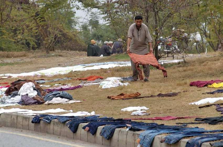 اسلام آباد: ایک دھوبی کپڑے دھونے کے بعد خشک کرنے کے لیے سڑک ..
