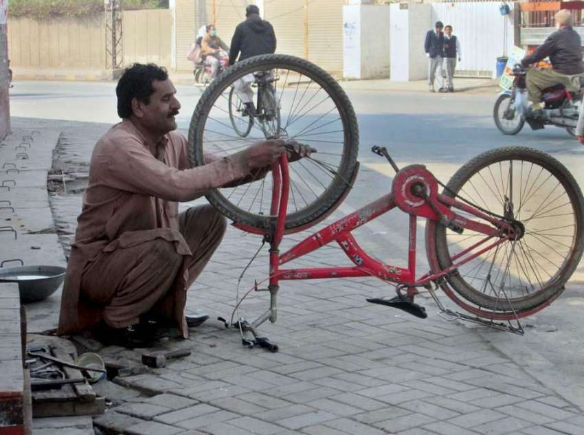فیصل آباد: ایک مکینک سائیکل مرمت کر رہا ہے۔