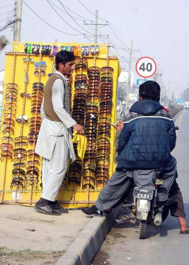 فیصل آباد: ایک محنت کش سڑک کنارے عینکوں کی سٹال لگائے گاہکوں ..