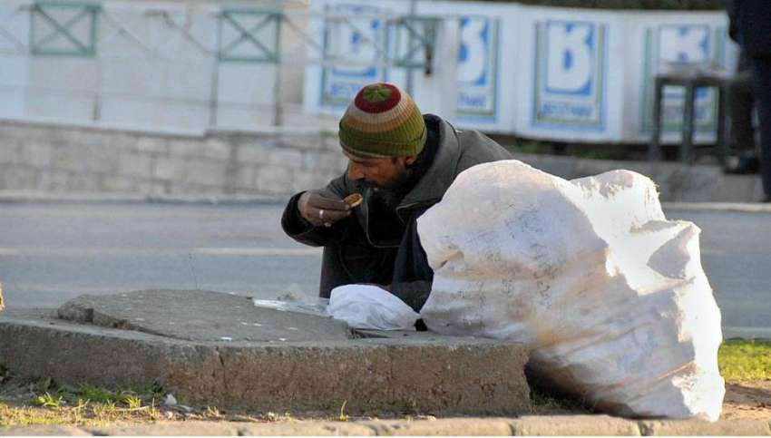 اسلام آباد: ایک خانہ بدوش شخص سڑک کنارے گرین بیلٹ پر بیٹھا ..
