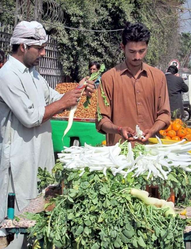 فیصل آباد: ایک شہری ریڑھی بان سے مولیاں خرید رہا ہے۔