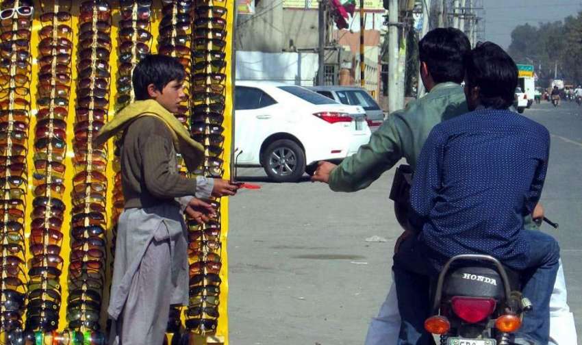فیصل آباد: ایک محنت کش سڑک کنارے عینکوں کا سٹال لگائے گاہکوں ..