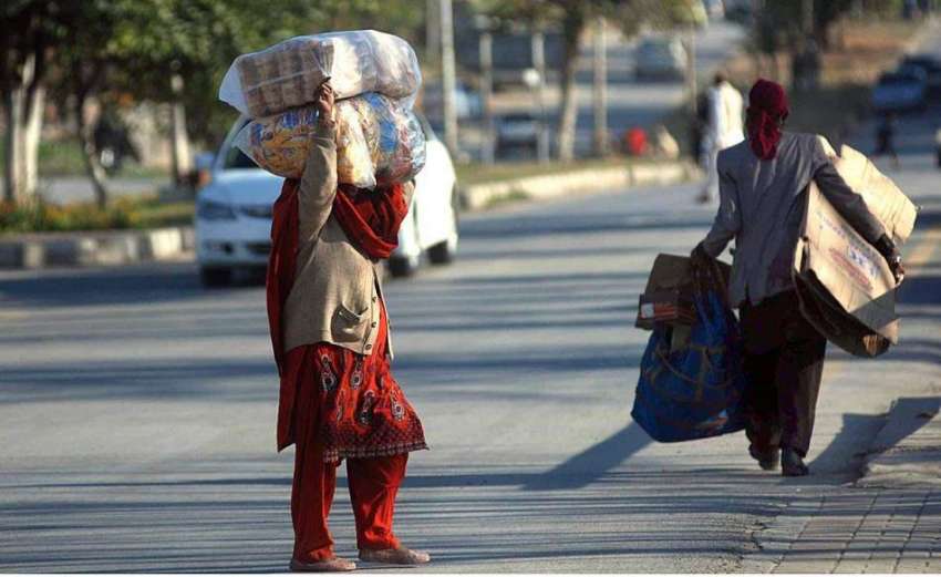 اسلام آباد: ایک خاتون سر پر بھائی سامان اٹھائے اپنی منزل ..