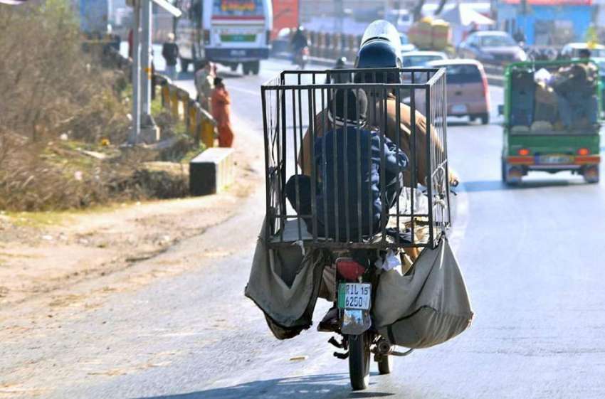 اسلام آباد: ایک موٹر سائیکل سوار اپنے بچے کے ہمرا ہ سامان ..