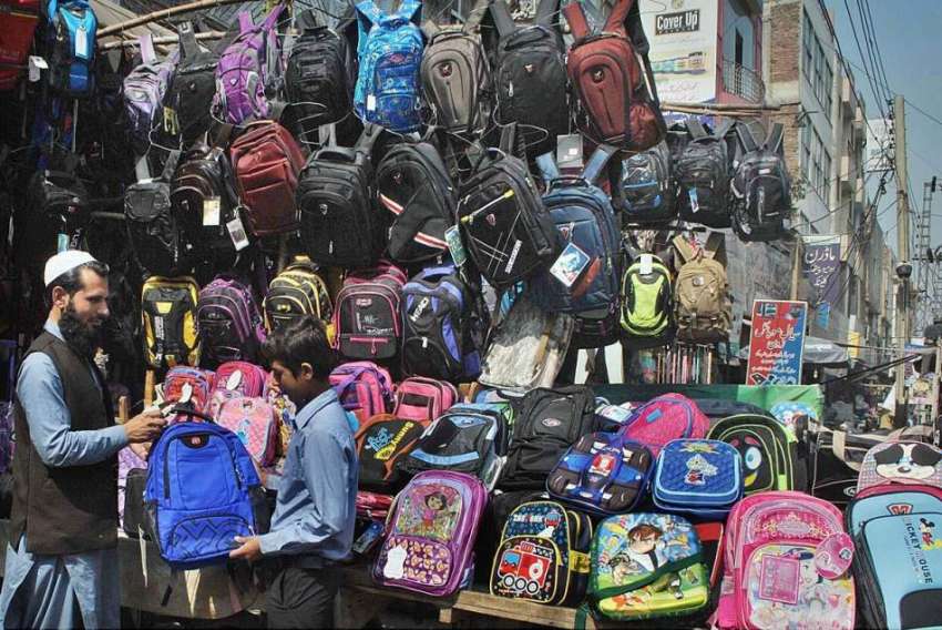 لاہور: ایک دوکاندار سڑک کنارے بچوں کے سکول بیگ لگائے گاہکوں ..