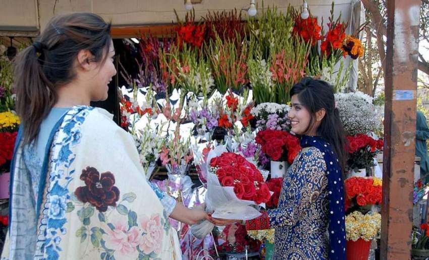 اسلام آباد: ایک خاتون اپنی دوست کو پھولوں کا گلدستہ دیتے ..