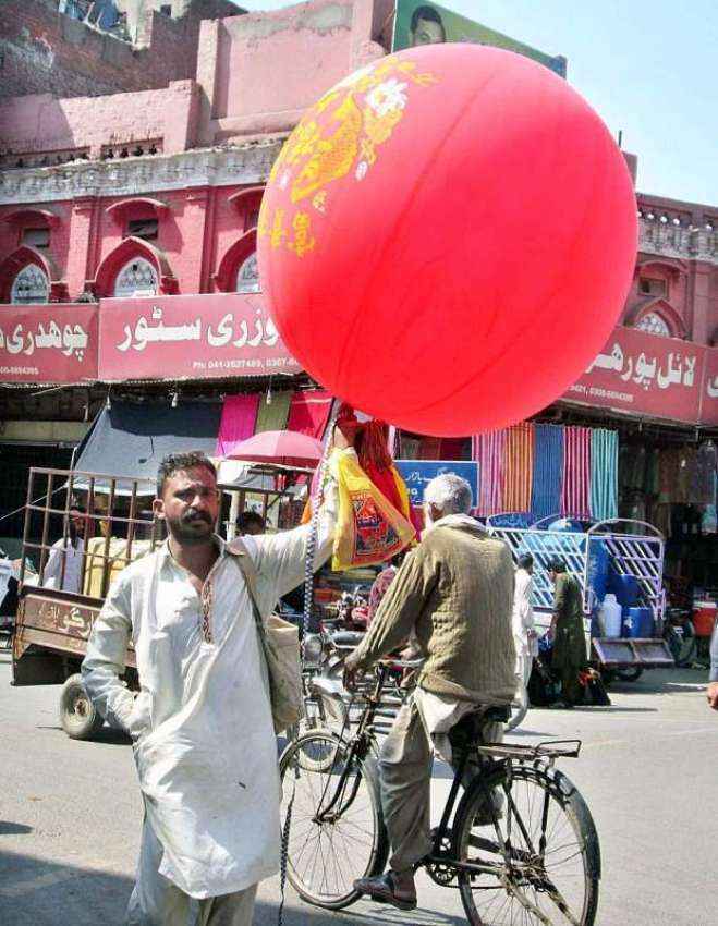 فیصل آباد: ایک محنت کش پھیری لگا کر بچوں کے غبارے فروخت کر ..