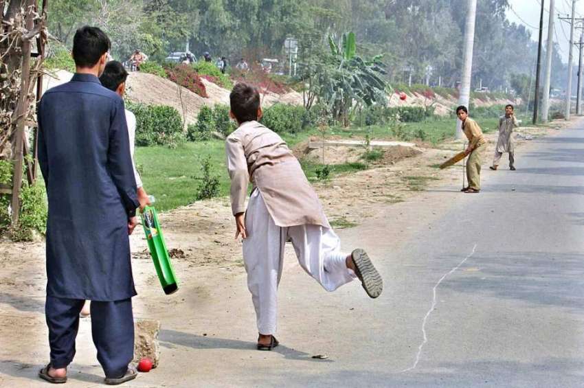 فیصل آباد: بچے سروس روڈ پر کرکٹ کھیل رہے ہیں۔