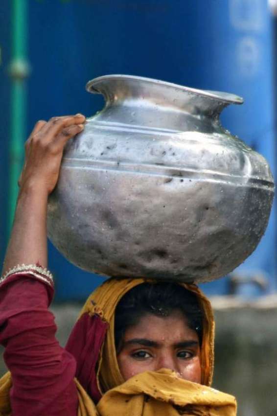 لاہور: ایک خاتون دیگچے میں پینے کا پانی سرپر اٹھائے جا رہی ..