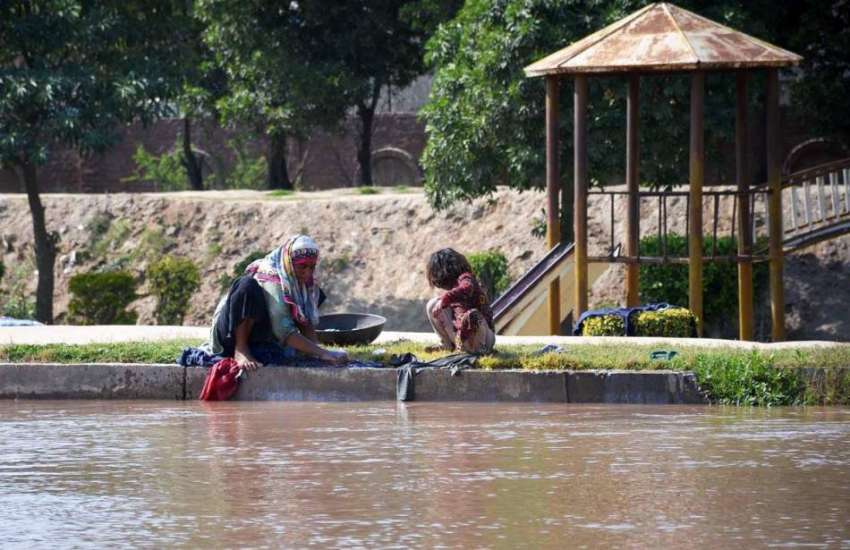 فیصل آباد: ایک خانہ بدوش خاتون اپنی بچی کے ہمراہ نہر کنارے ..