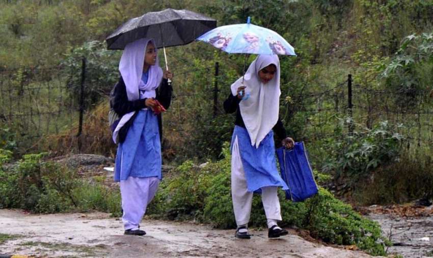 راولپنڈی: صبح سویرے ہونوالے بارش کے دوران بچے چھتری تھامے ..