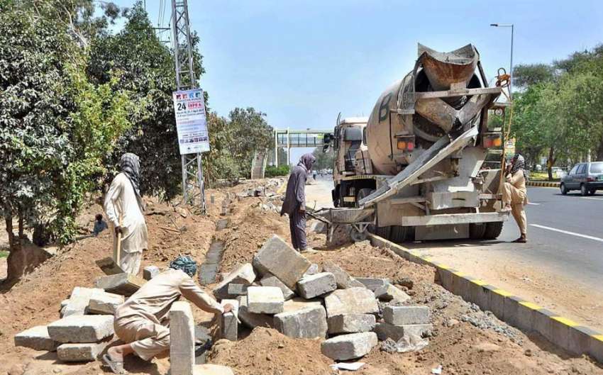 لاہور: مزدور کینال روڈ پر فٹ پاتھ کے تعمیراتی کام میں مصروف ..