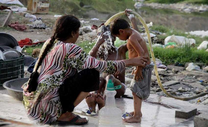 لاہور: ایک خانہ بدوش خاتون گرمی کی شدت سے بچاؤ کے لیے بچوں ..