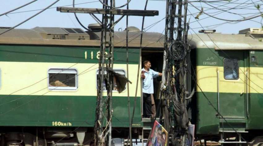 لاہور: ایک مسافر ٹرین کے دروازے میں کھڑا ہو کر سفر کر رہا ..