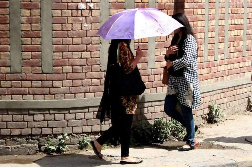 لاہور: ایک طالبہ دھوپ سے بچنے کے لیے چھتری تانے جا رہی ہے۔