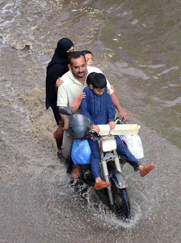کراچی: موٹر سائیکل سوار فیملی برساتی پانی سے گزر رہی ہے۔