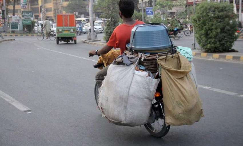 لاہور: ایک شخص موٹر سائیکل پر برتن فروخت کرنے کے لیے جا رہا ..