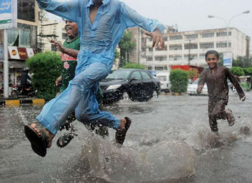 لاہور: شہر میں ہونیوالی موسلا دھار بارش کے دوران بچے سڑک ..
