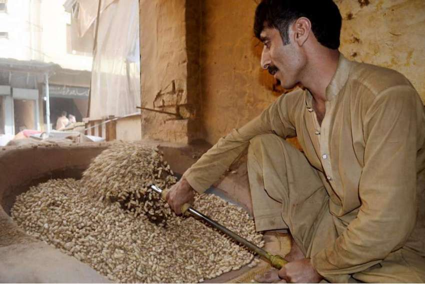 راولپنڈی: گنجمنڈی موڑ میں ایک محنت کش مونگ پھلیاں بھوننے ..