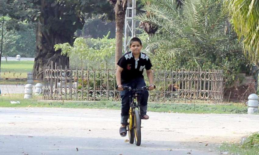لاہور: ایک بچہ باغ جناح میں پابندی کے باوجود سائیکل چلا رہا ..