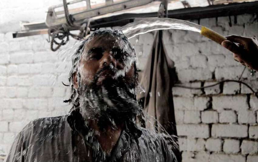 راولپنڈی: گرمی کی شدت کم کرنے کے لیے ایک مزدور سر پر پانی ..