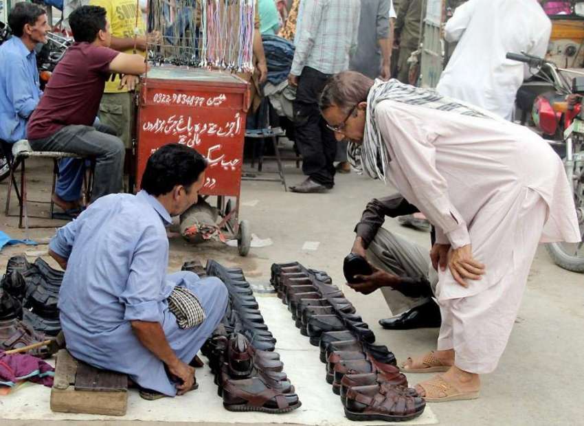 لاہور: ایک شہری راوی روڈ پر سڑک کنارے لگے سٹال سے جوتے خرید ..