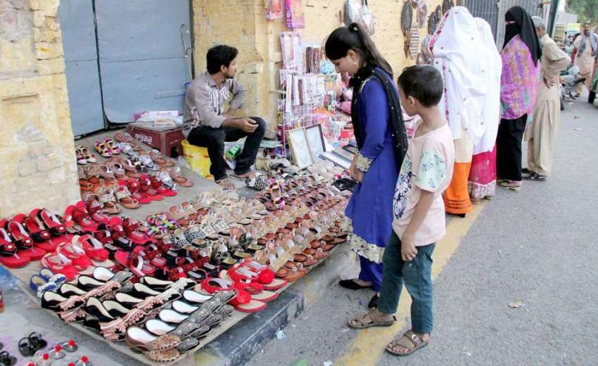 لاہور: ایک لڑکی شاہی قلعہ کے باہر لگے سٹال سے جوتا خرید رہی ..