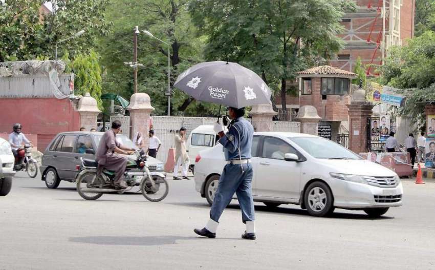لاہور: مال روڈ پر ٹریفک وارڈن دھوپ سے بچنے کے لیے چھتری تانے ..
