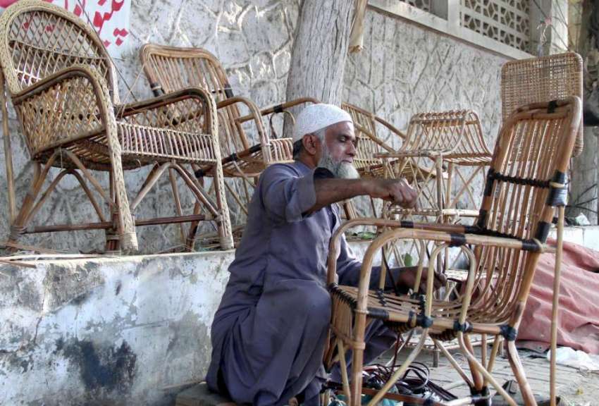 کراچی: ایک معمر محنت کش فٹ پاتھ پر بیٹھا کرسیاں بنا رہا ہے۔