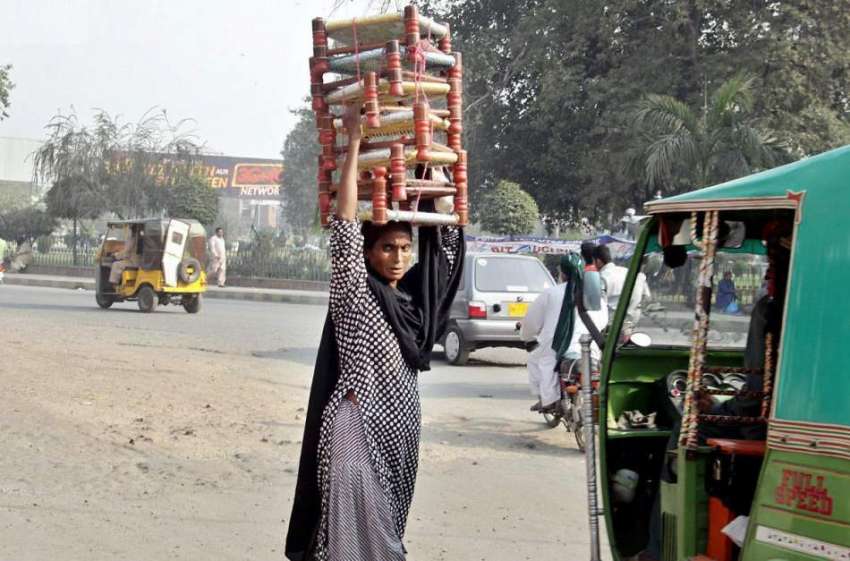 لاہور: ایک محنت کش خاتون بیٹھنے کے لیے لکڑی کی پیڑیاں اپنے ..
