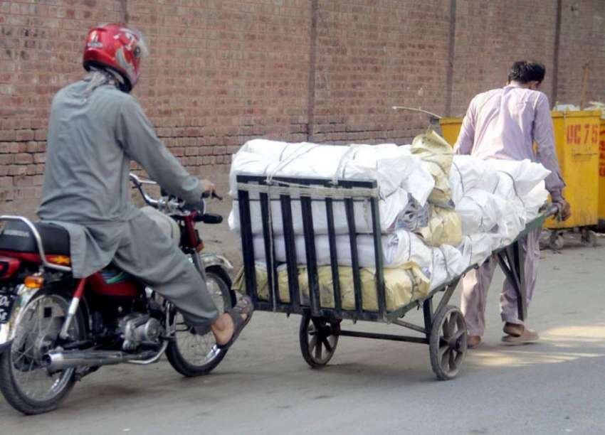 لاہور: ایک موٹر سائیکل سوار بھاری سامان رکھ کر لیجانے والے ..