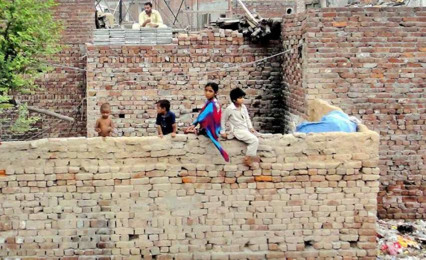 لاہور: شاہدرہ کے علاقہ میں بچے خستہ حال دیوار پر بیٹھے ہیں ..