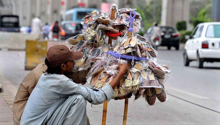 راولپنڈی: ایک محنت کش پھیری لگا کر جوتے فروخت کر رہا ہے۔