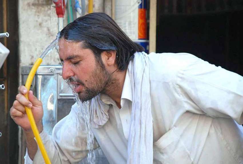 پشاور: شہری گرمی کی شدت کم کرنے کے لیے منہ پر پانی ڈال رہا ..