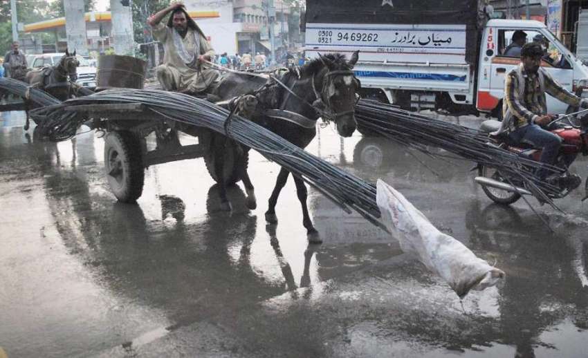 لاہور: مغلپورہ کے علاقہ میں بارش سے بچنے کے لیے ریڑھی بان ..