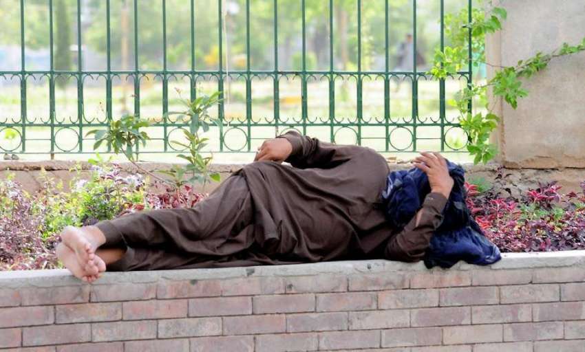 راولپنڈی: مزدور تھک ہار کر لیاقت باغ کے باہر بنے لان میں ..