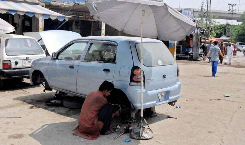 راولپنڈی: دھوپ سے بچنے کے لیے ایک محنت کش چھتری لگائے گاڑی ..