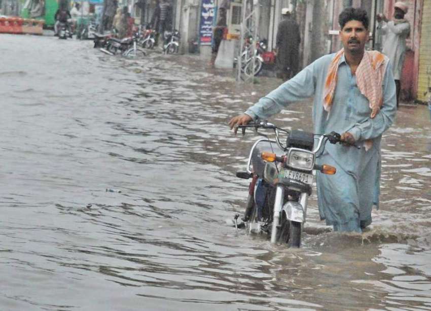 لاہور: شہر میں ہونے والی موسلا دھار بارش کے بعد ایک شہری ..