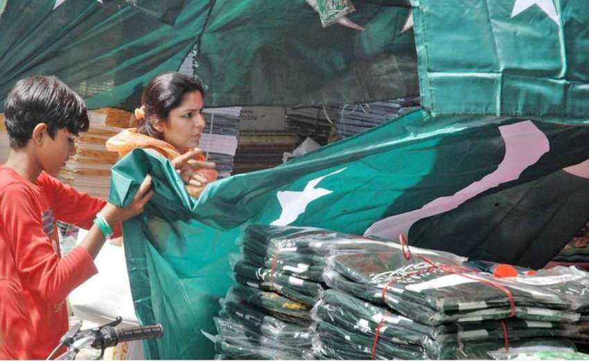 لاہور: ایک خاتون یوم آزادی کے لیے اردو بازار سے قومی پرچم ..