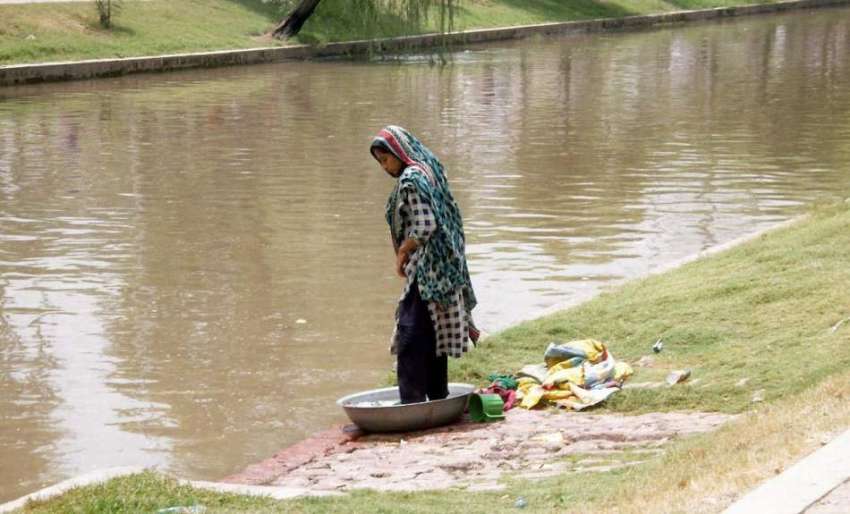 لاہور: ایک خاتون نہر کنارے کپڑے دھو رہی ہے۔