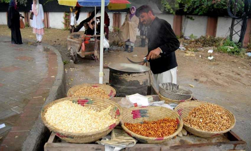 راولپنڈی: ایک مینت کش مکئیت کے دانے بھوننے می ں مصروف ہے ..