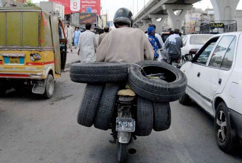 راولپنڈی: ایک شخص موٹر سائیکل پر ٹائر لادھے مری روڈ سے گزر ..