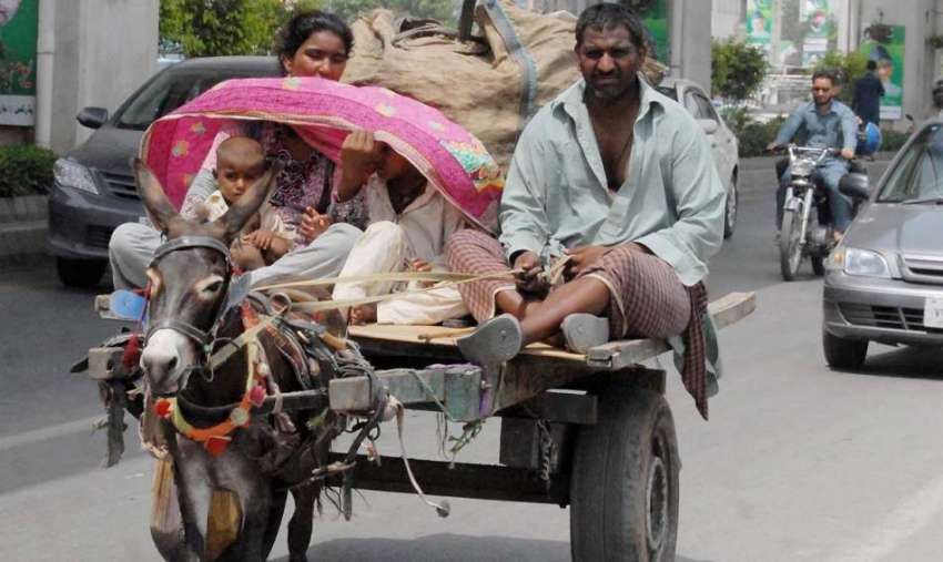 راولپنڈی: ایک خانہ بدوش خاندان دھوپ سے بچنے کے لیے چادر سے ..